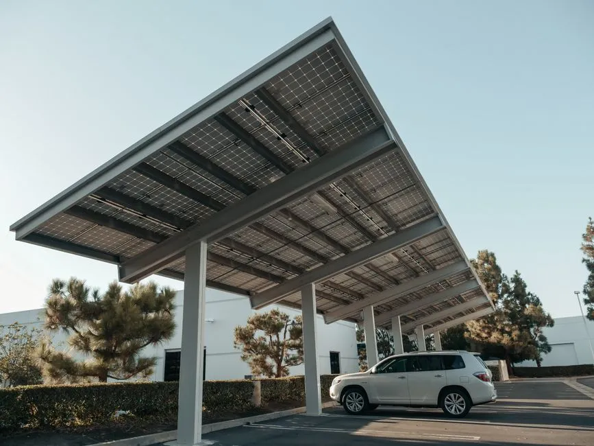 Nahaufnahme von Solarmodulen auf einer Metallstruktur mit durchscheinendem Sonnenlicht, das nachhaltige Energie betont.